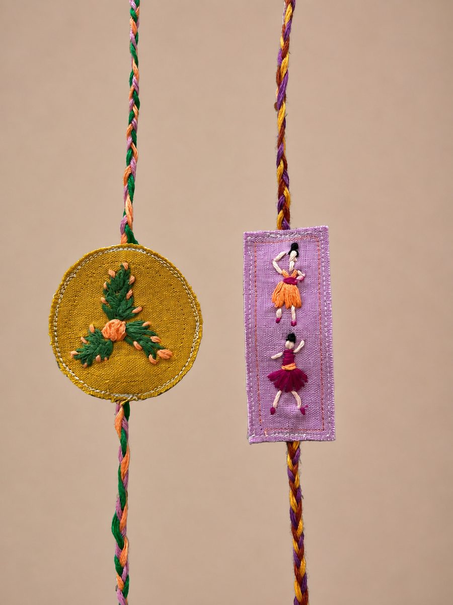 Two hand-embroidered fabric rakhis on braided threads